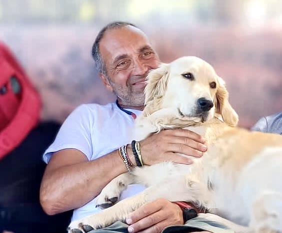 Vittorio Franco, che segue l'asilo, seduto con Nala, una golden retriever, in braccio